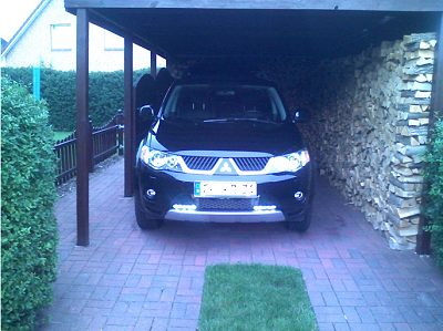 Der Outlander mit eingeschaltetem Tagfahrlich in einem Carport. 